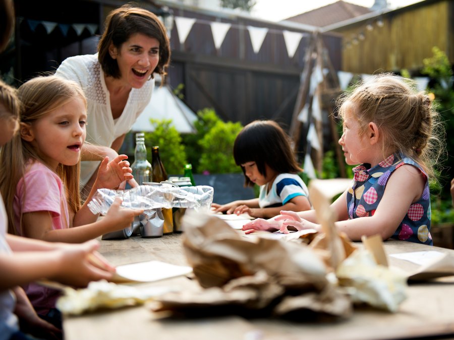 A teacher and three children working together at an outdoor table