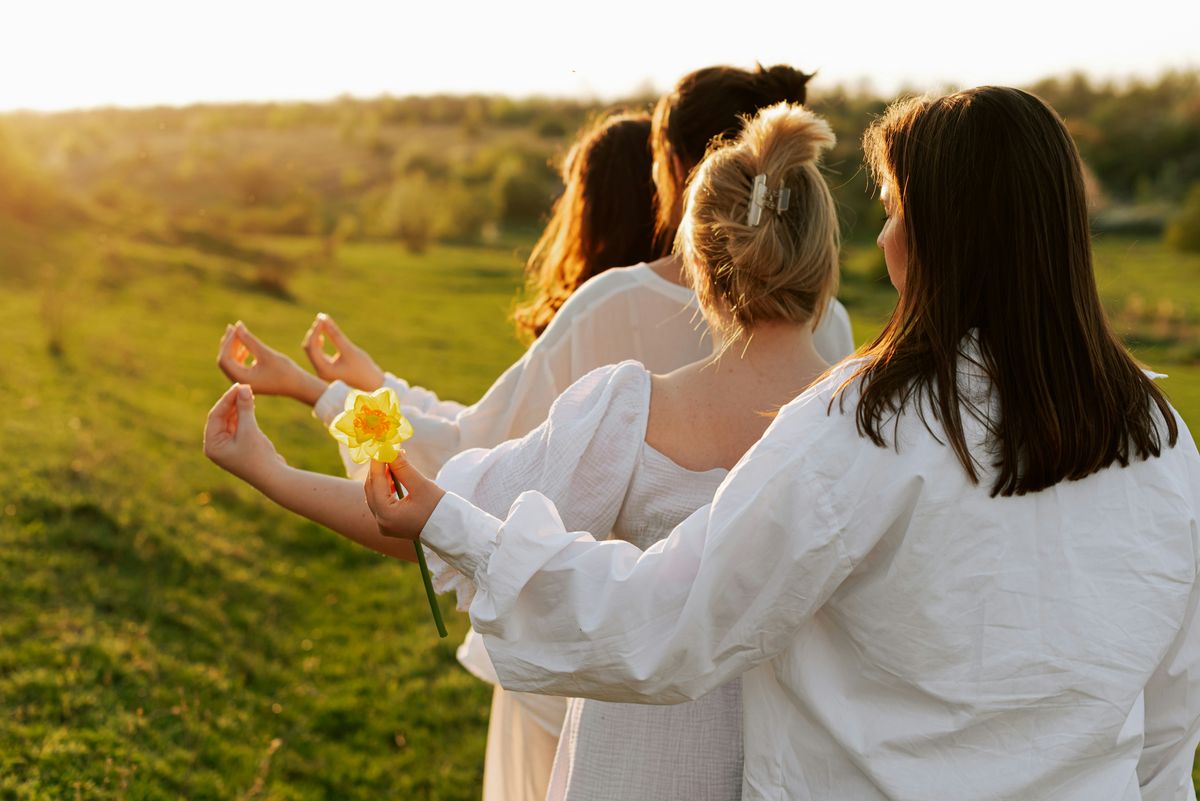 Women gathered in a golden field, flowers in hand